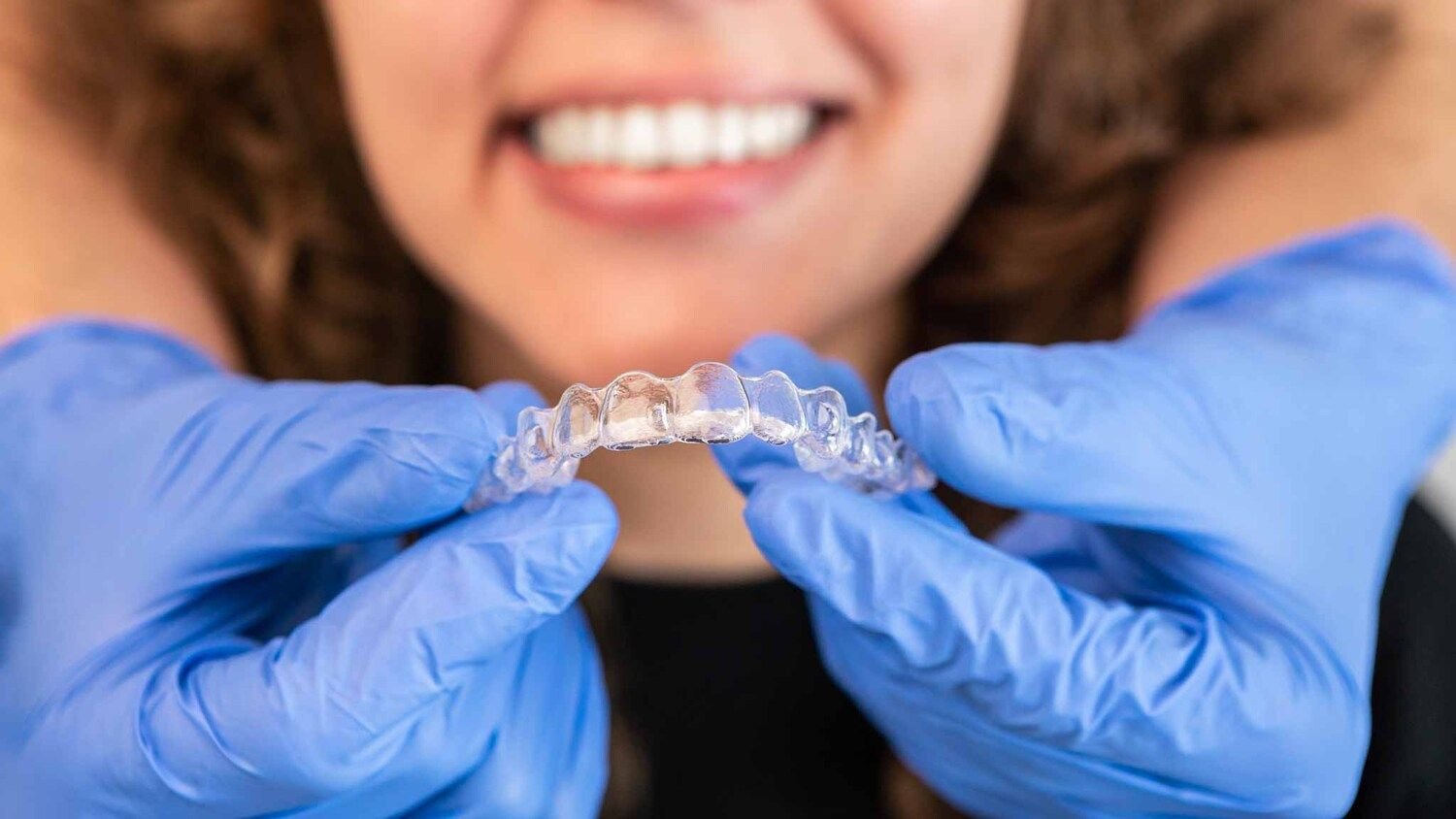 Dentist putting invisible transparent braces on woman teeth